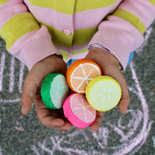 Load image into Gallery viewer, Colorful lemon-shaped bath bombs held by a child against a chalk-drawn background