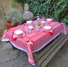Load image into Gallery viewer, Outdoor table setting with a red and white patterned tablecloth, glasses, and plates.