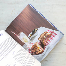 Load image into Gallery viewer, Open book with a photograph of a sandwich and drink on a wooden table