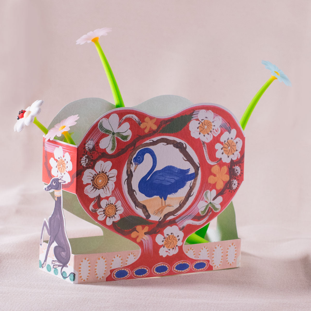 Colorful heart-shaped card with floral and swan design on a beige background