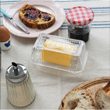 Load image into Gallery viewer, Butter dish with butter, toast, and a jar of jam on a tablecloth.
