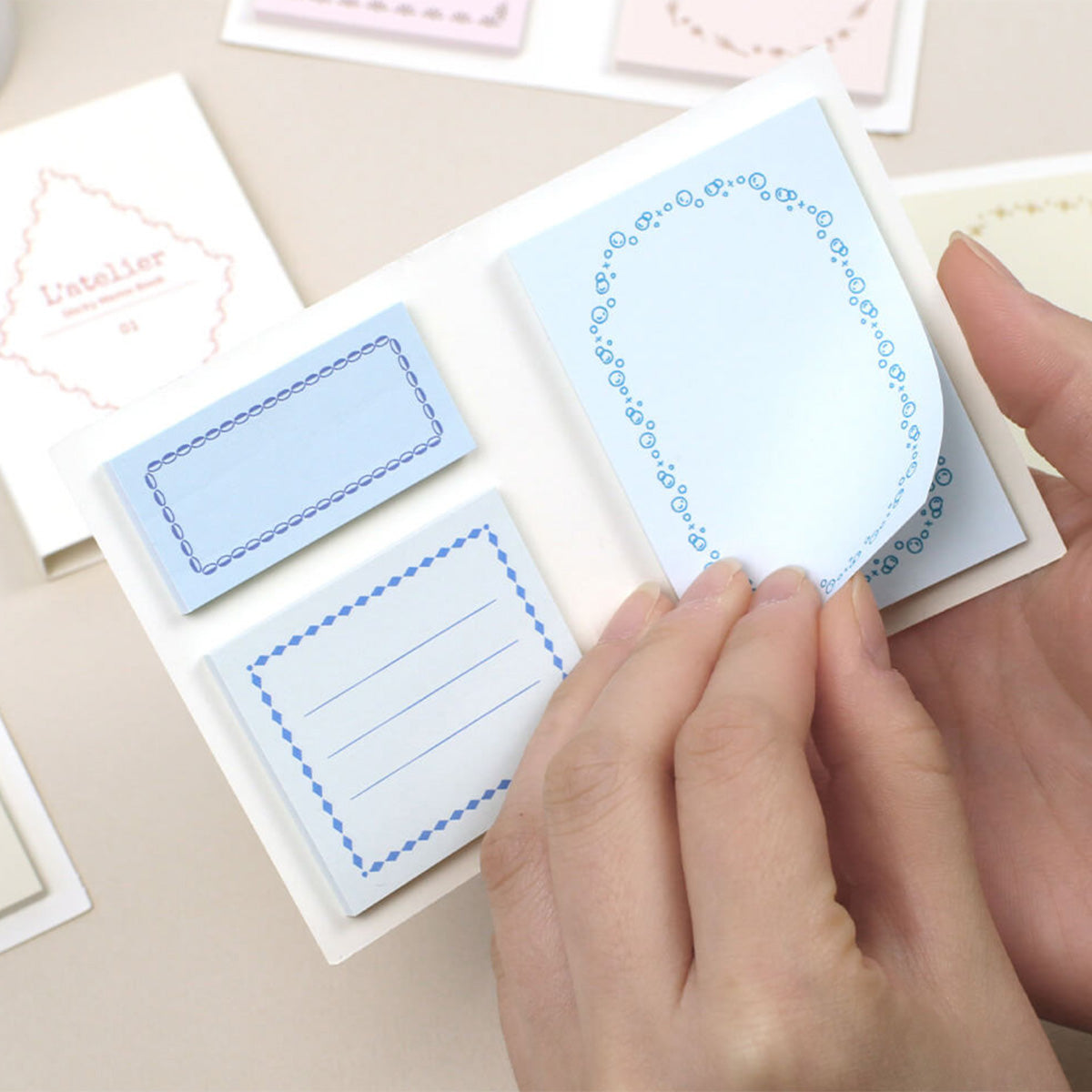 Hand holding a small blue card with decorative border on a beige surface